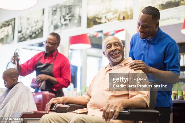 black barber talking to customer in retro barbershop - african american hair salon stock pictures, royalty-free photos & images