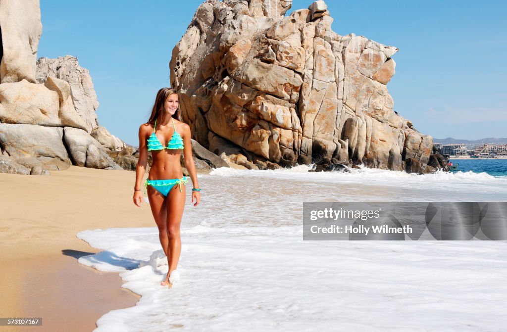 Caucasian woman walking in waves on beach