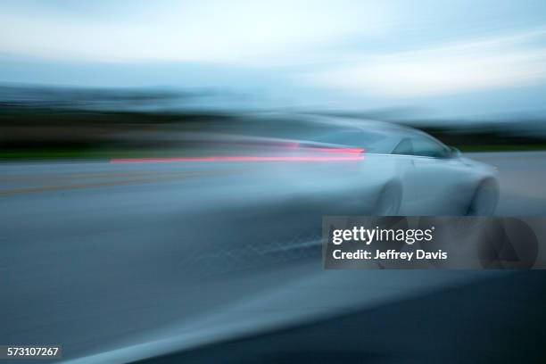 blurred view of car driving on road - car speeding stock-fotos und bilder