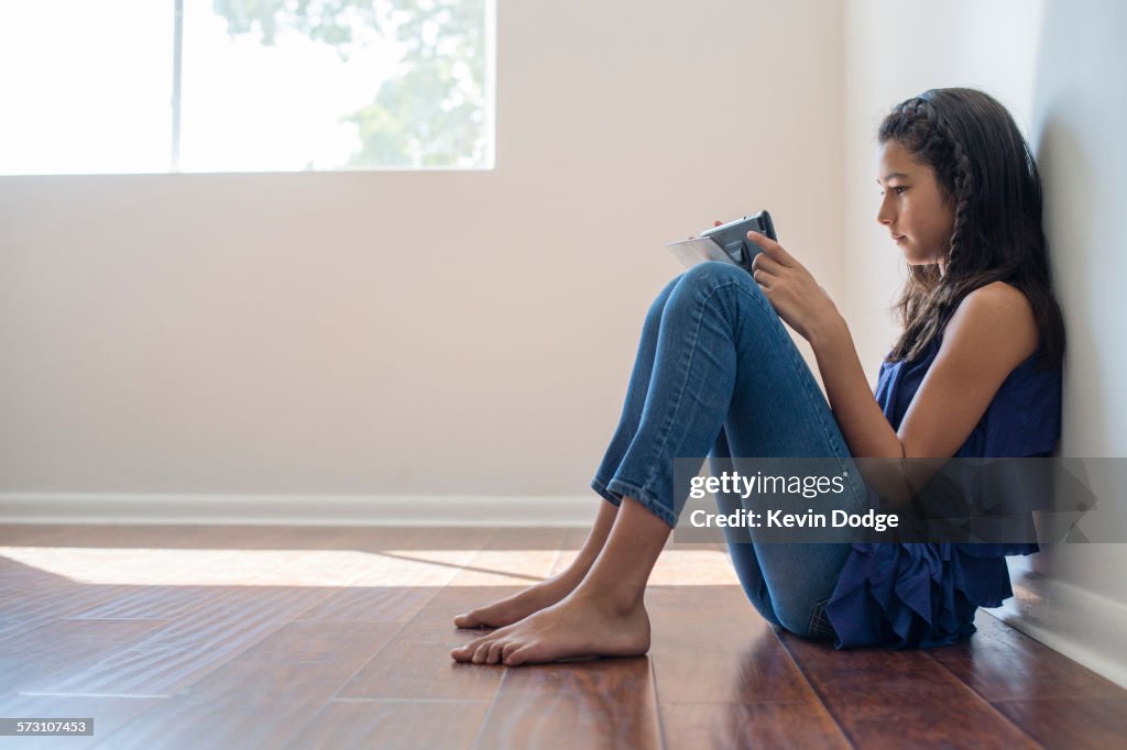 Mixed race girl using digital tablet in empty room