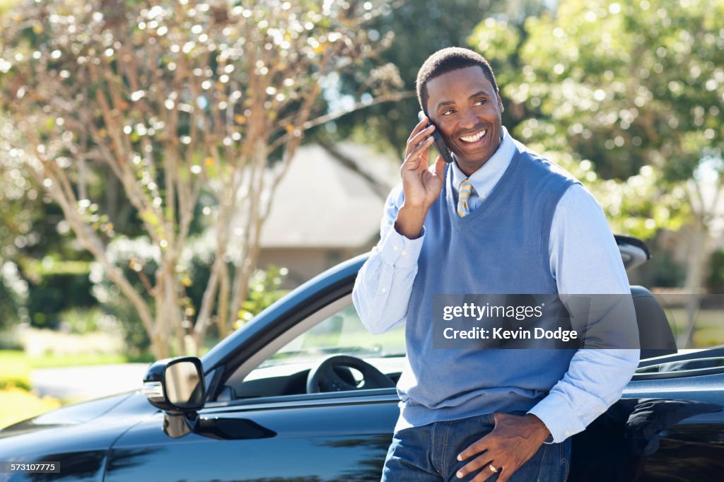 Black man talking on cell phone at convertible