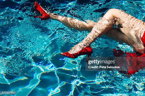 legs of woman wearing high heels in swimming pool - chaussures rouges photos et images de collection