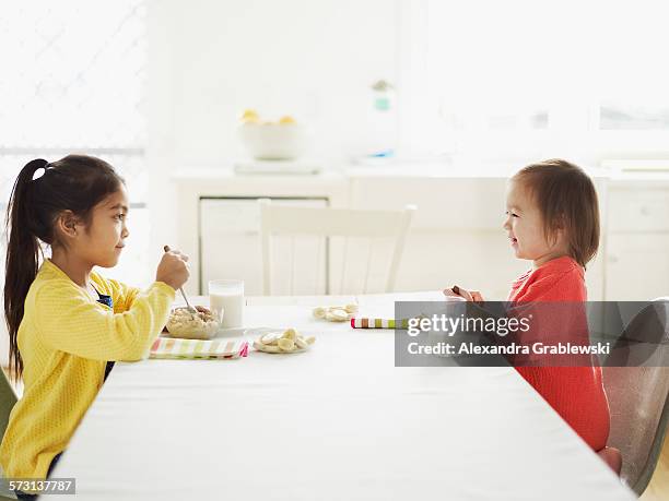 sisters eating oatmeal - long table stock pictures, royalty-free photos & images