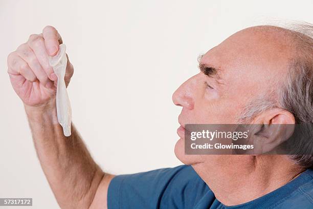 side profile of a senior man holding a condom - condom bildbanksfoton och bilder