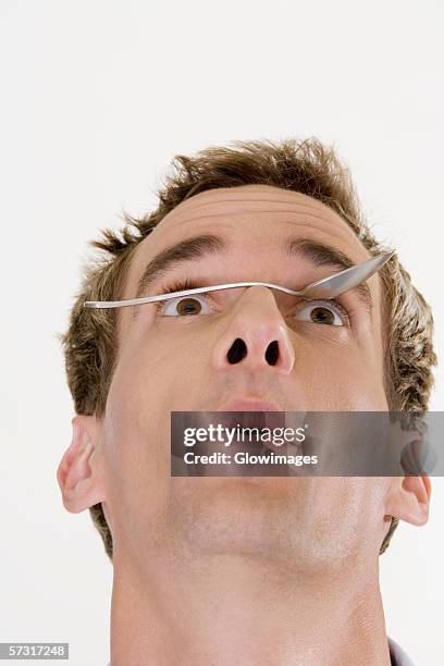 close-up of a young man balancing a spoon on his nose - menschliche nase stock-fotos und bilder