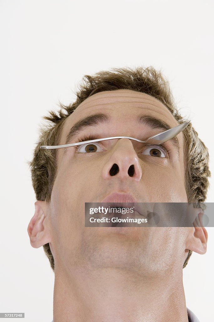 Close-up of a young man balancing a spoon on his nose