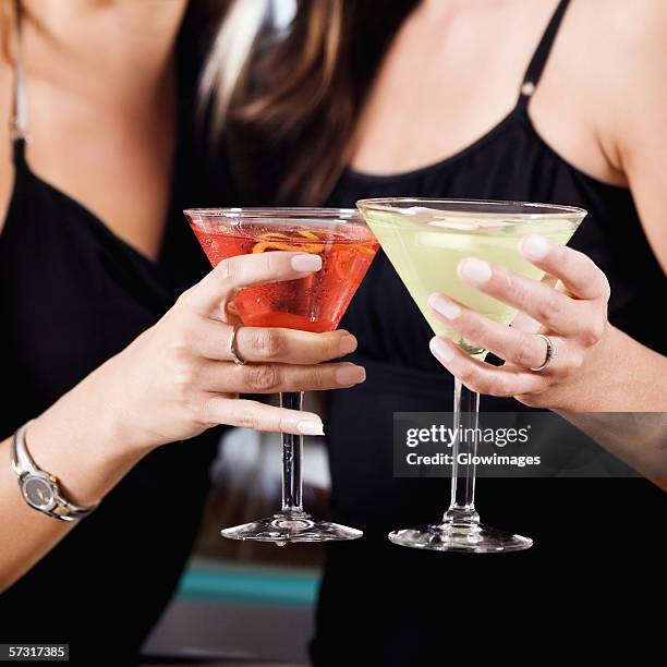 mid section view of two young women toasting martinis - cocktail ring stock-fotos und bilder