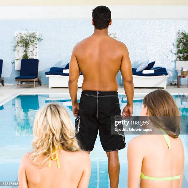 rear view of a mid adult man standing in front of two young women at the poolside - woman back pillow blonde stock pictures, royalty-free photos & images