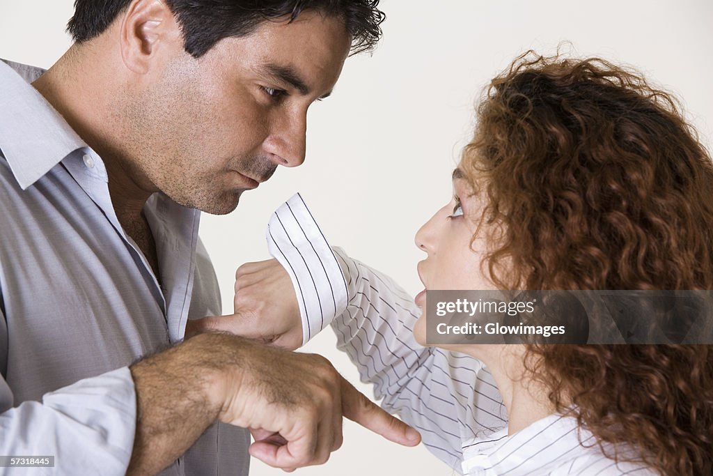 Side profile of a mid adult man and a young woman arguing