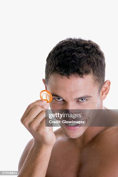 portrait of a young man holding a condom - condoom stockfoto's en -beelden