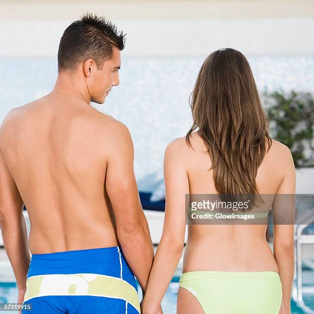 rear view of a young couple standing at the poolside - seitenblick stock-fotos und bilder
