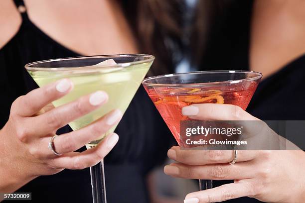 mid section view of two young women toasting martinis - cocktail ring stock-fotos und bilder