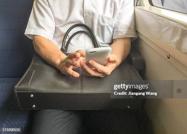 Man tapping on a smartphone in the seat of train