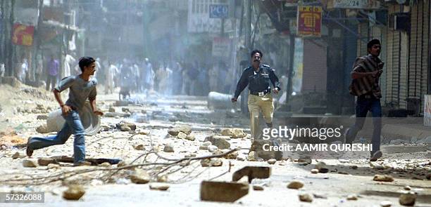 Pakistani policeman chases young men following violent protests in the aftermath of a bomb blast which left 57 dead in Karachi, 12 April 2006....