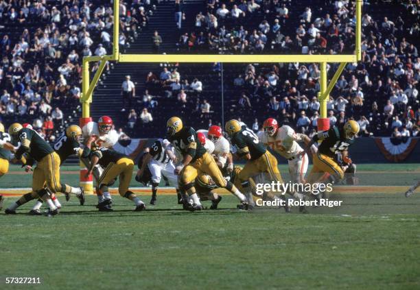 American professional football player Bart Starr , quarterback of the Green Bay Packers, runs away after handing off the ball to teammate Jim Taylor...