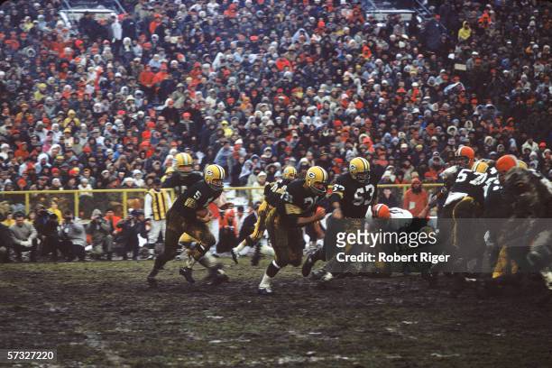 American professional football player Paul Hornung of the Green Bay Packers takes the ball in a hand off from quarterback Bart Starr and follows Jim...