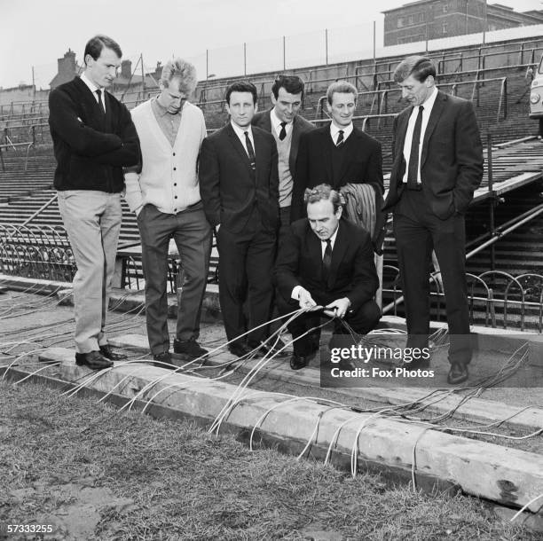 Arsenal manager Billy Wright explains the stadium's new underground 'blanket' to members of his team - Jimmy Magill, Ian Ure, Johnny MacLeod, Alan...