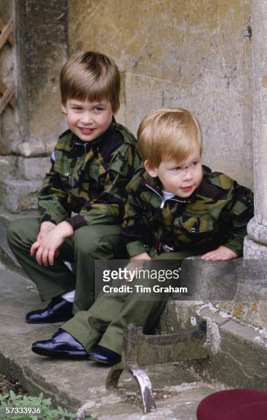 Prince Harry and Prince William sit together on the steps of Highgrove House wearing army uniforms on July 18, 1986 in Tetbury, England.