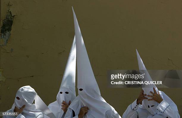 Penitents adjust their headware while walking to the start of the 'Los negritos' brotherhood procession in Seville during holy week, 13 April 2006....