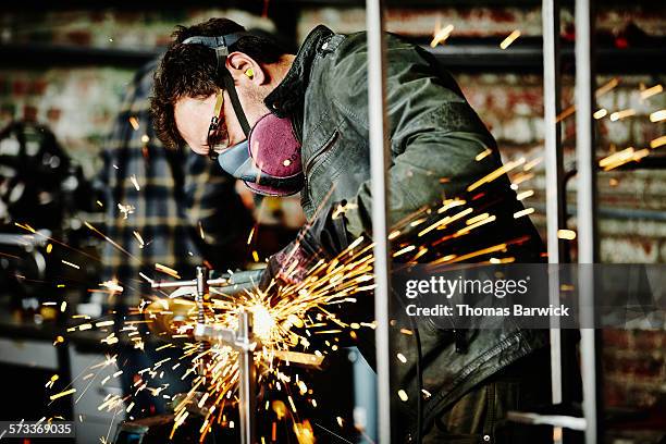 metal worker cutting steel bar in metal shop - metalwork stock-fotos und bilder