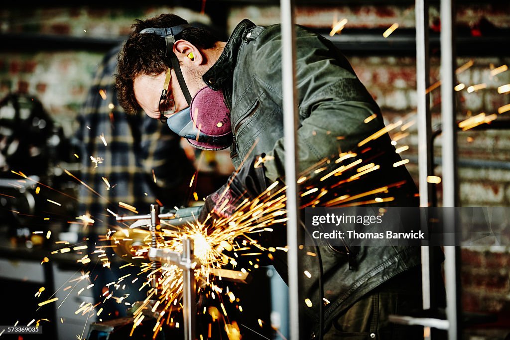 Metal worker cutting steel bar in metal shop