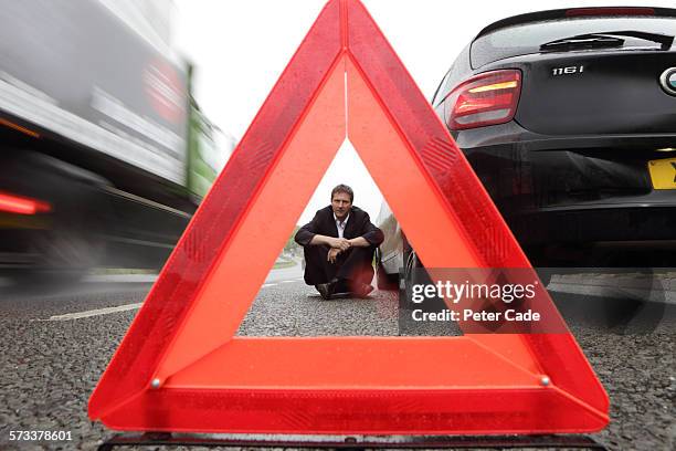 man viewed through warning triangle, broken car - roadside assistance stock-fotos und bilder