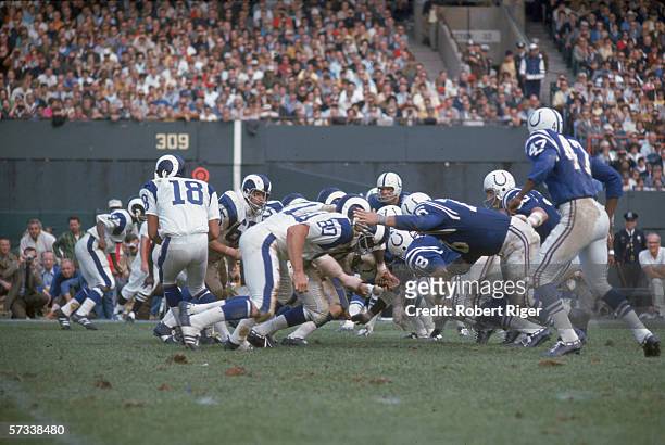 The Baltimore Colts defense goes after the Los Angeles Rams offensive line after Rams quarterback American football player Roman Gabriel hands off...