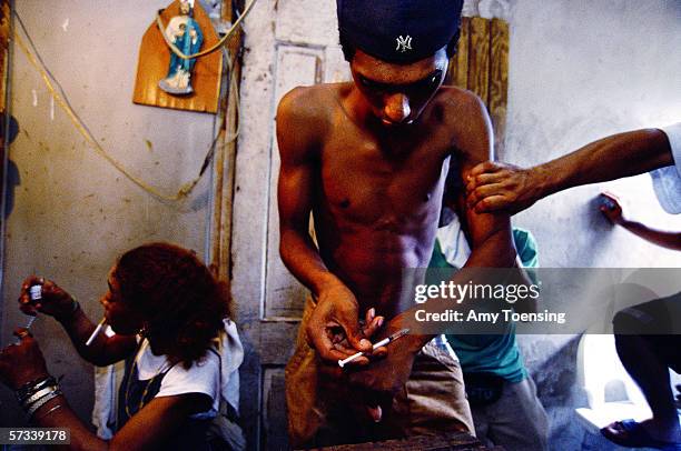 Heroin addicts shoot up on October 10, 2001 in Loiza Aldea, Puerto Rico. The owners of this crack house pay the police to stay away so heroin addicts...