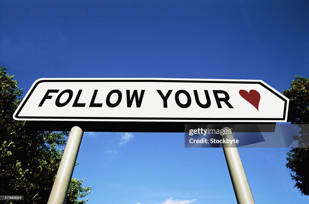 Low angle view of a road sign saying follow your heart