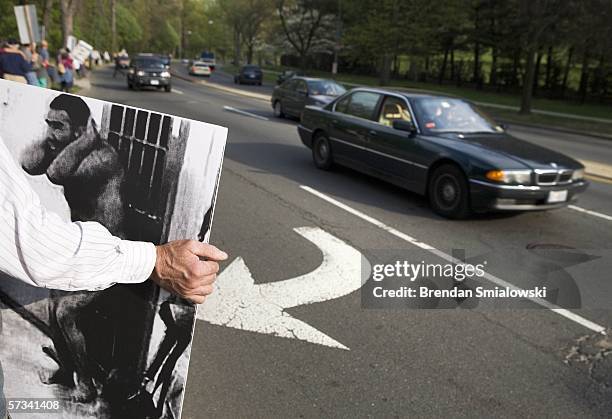 An activist holds up a large picture of a prisoner to passing cars on Wisconsin Avenue during a vigil outside the residence of Vice President Dick...