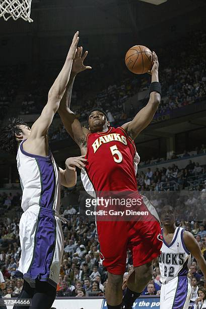 Josh Smith of the Atlanta Hawks drives to the basket against Andrew Bogut of the Milwaukee Bucks as Michael Redd of the Bucks looks on during the NBA...
