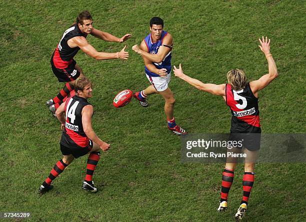 Lindsay Gilbee of the Bulldogs gets a handball away despite pressure from his Bombers opponents during the round three AFL match between the Essendon...