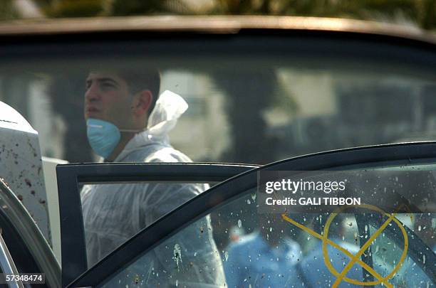 An Israeli police forensic expert is seen through a window of a car damaged in the explosion and covered with human remains at the scene where a...