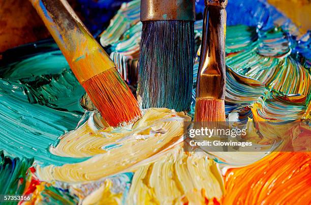 high angle view of paintbrushes mixing paint on a palette - oil paint stock pictures, royalty-free photos & images