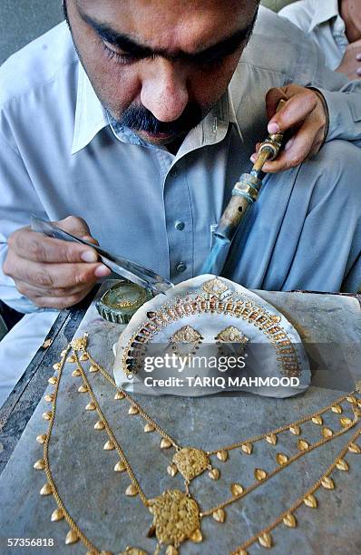 Pakistani jewellery prepares a necklace at a gold shop in Peshawar, 18 April 2006. The gold price has risen in Pakistan over the last several weeks...