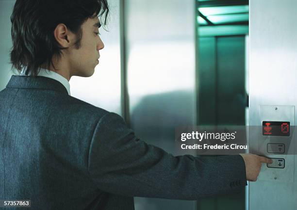 young man in suit pushing button for elevator - elevator button stock pictures, royalty-free photos & images
