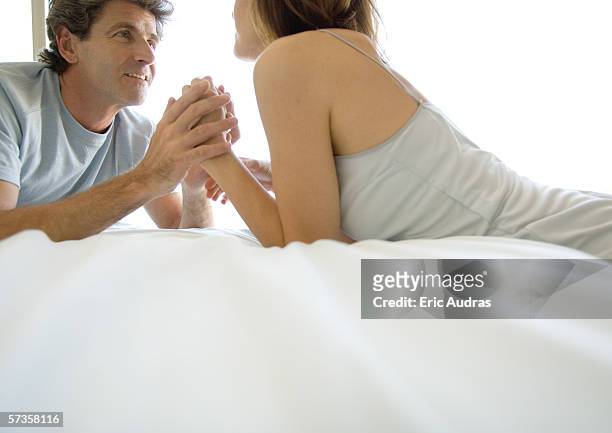 couple lying on bed, holding hands - temi legati alla sessualità foto e immagini stock