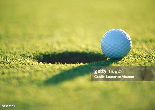 golf ball at edge of hole, close-up - golf stock-fotos und bilder