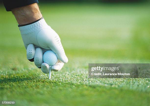 golfer's gloved hand teeing up, close-up - golf tee foto e immagini stock