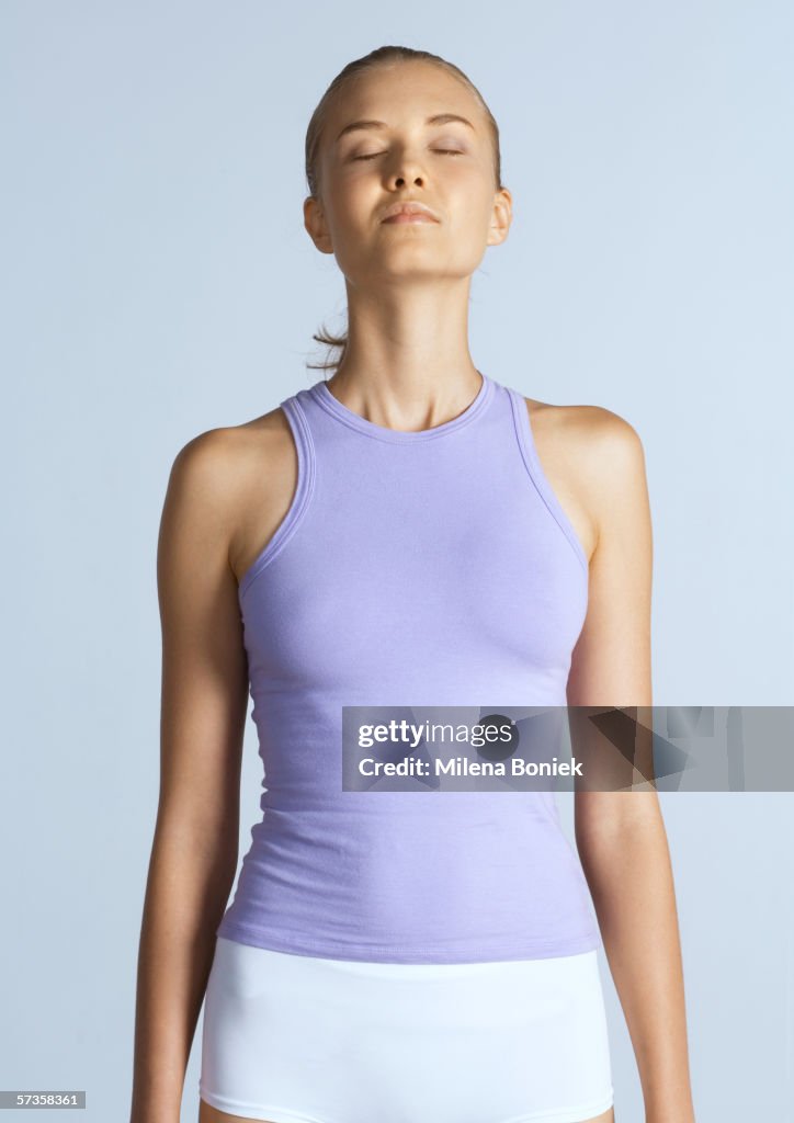 Woman standing with arms by sides and eyes closed