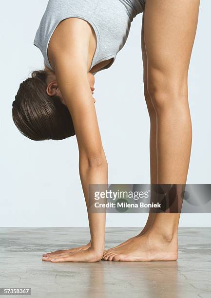 woman doing standing forward bend - zehenspitzen berühren stock-fotos und bilder