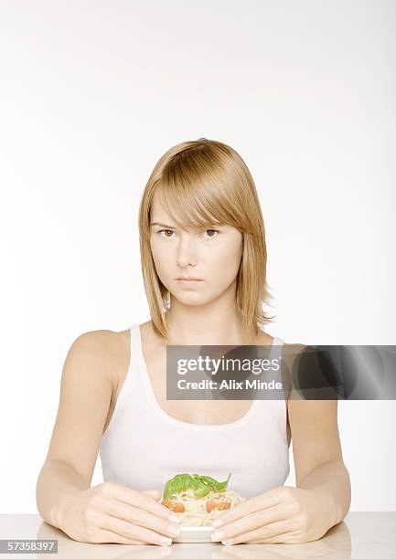 young woman with arms around plate of pasta - egoismus stock-fotos und bilder