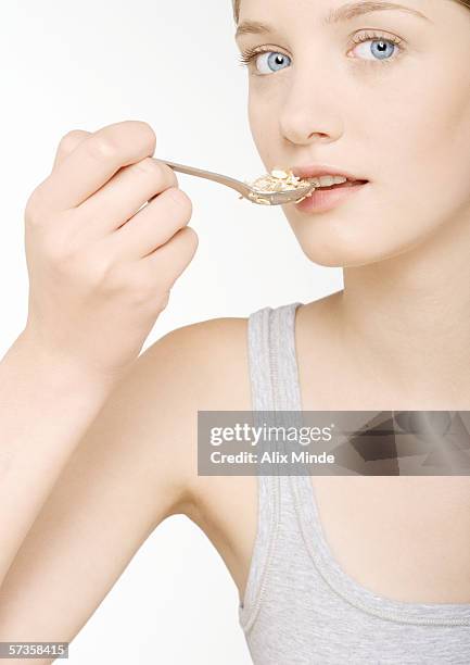 young woman eating cereal - spoon in hand stock-fotos und bilder