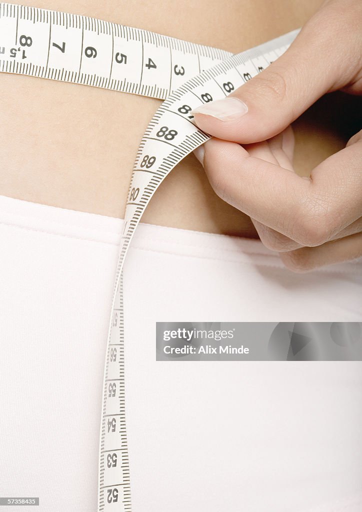 Woman measuring waist, extreme close-up