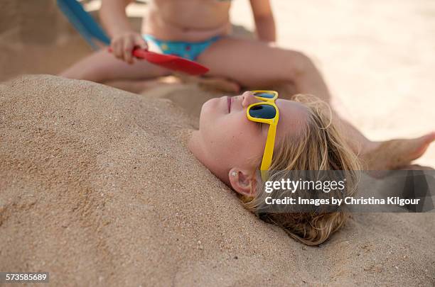 girl buried in sand by her sister - buried in sand stockfoto's en -beelden