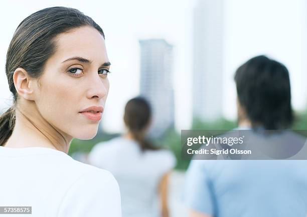 young woman looking over shoulder in urban park - over the shoulder view stock-fotos und bilder