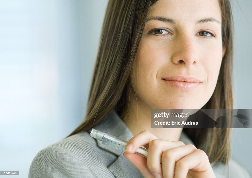Businesswoman holding pen, close-up, portrait