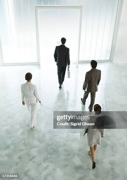 four executives walking across lobby toward exit - four people walking away stock pictures, royalty-free photos & images