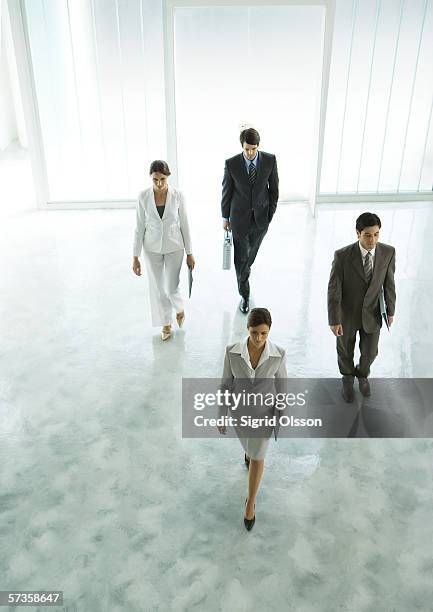 four executives walking through office building lobby - departure board front on fotografías e imágenes de stock