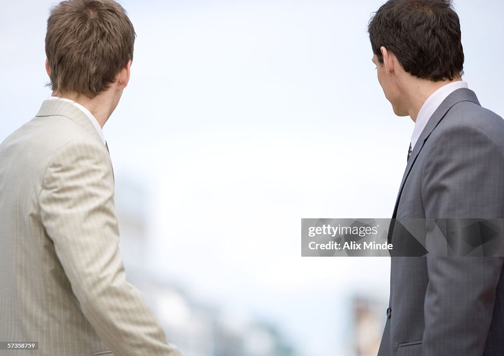 Two businessmen looking into the distance, rear view